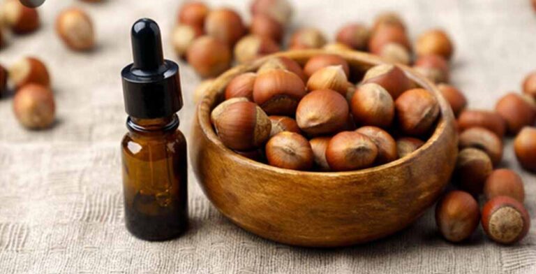 یک ظرف چوبی فندق و در کنارش روغن فندق
